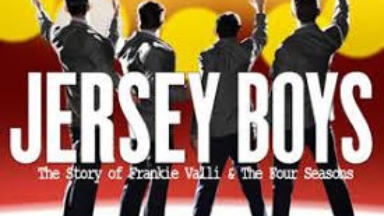 Four men with dark hair and dark suits are seen from behind, standing on a stage and each raising one hand to the audience. We see bright lights shining in the background and in the foreground the words "Jersey Boys, The Story of Frankie Valli and the Four Seasons" in white block letters.